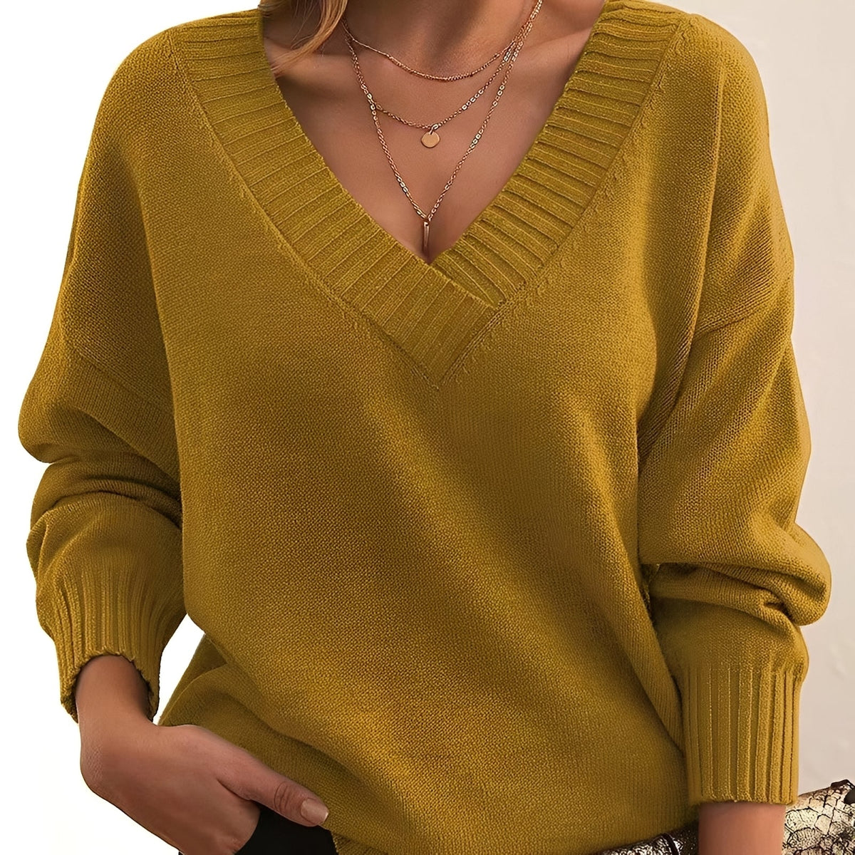 Suéter ligero holgado de mujer amarillo con escote pico y puños de punto acanalado.