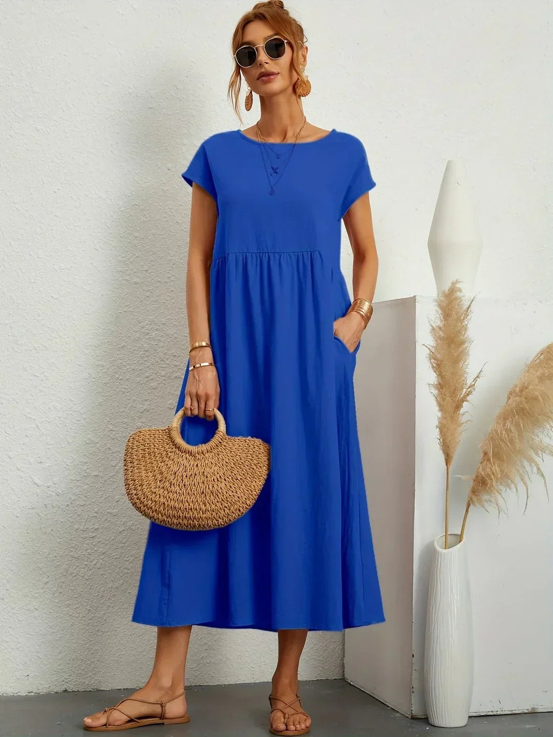 Vestido midi fluido azul con escote redondo y falda con vuelo fruncida.