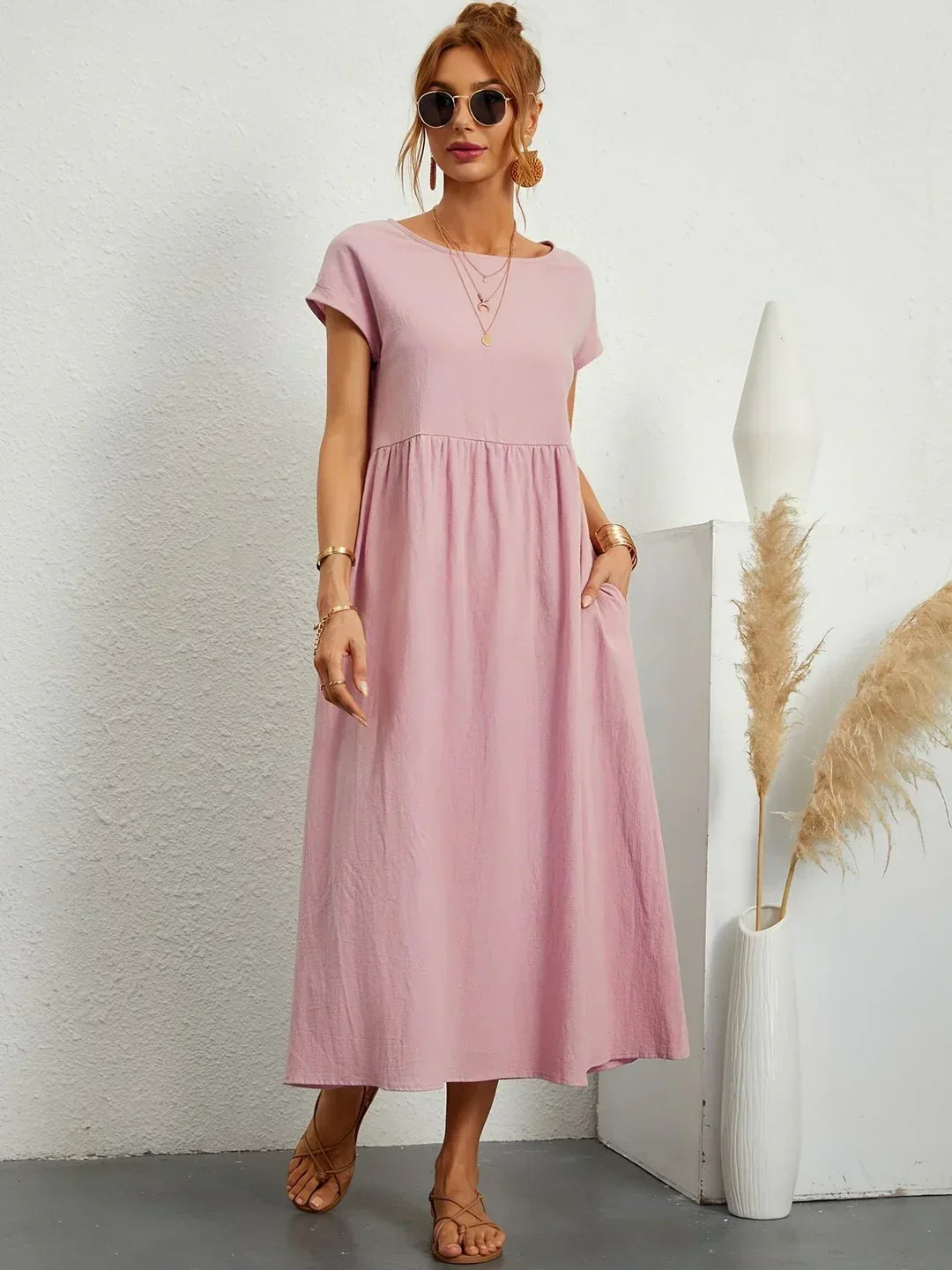 Vestido midi fluido rosa palo con escote redondo y fruncido en la cintura.