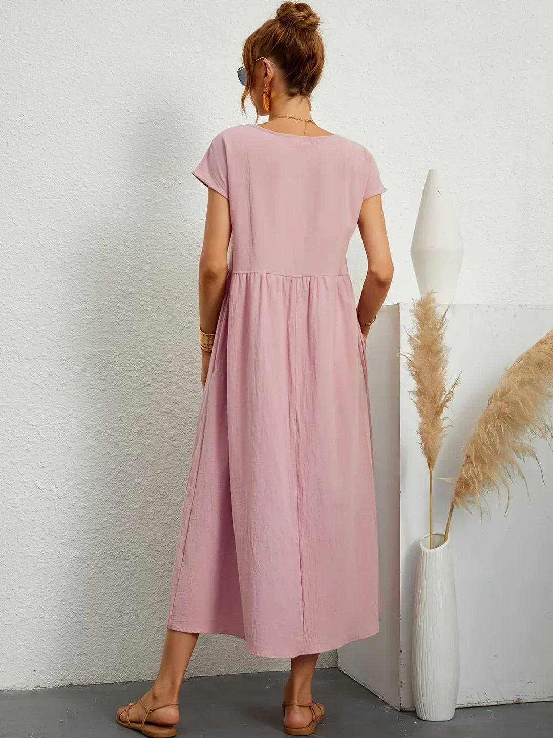 Vestido midi fluido rosa palo con espalda entera y falda con vuelo fruncida.