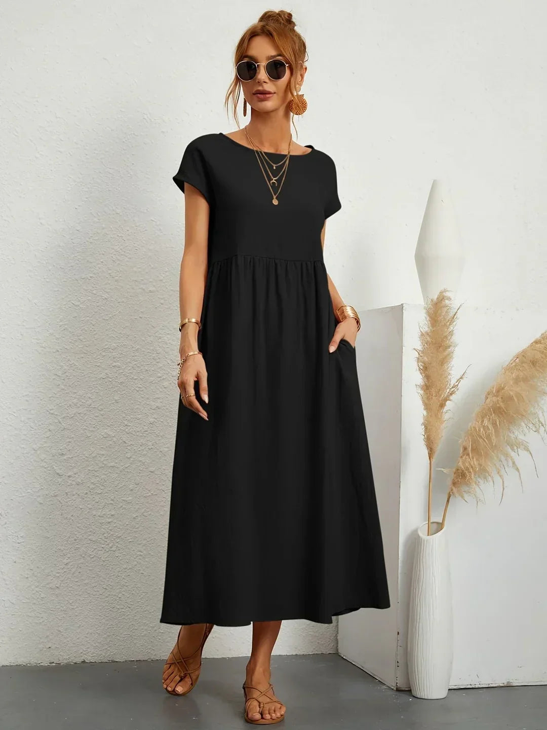 Vestido midi fluido negro con escote redondo y falda amplia con fruncidos.
