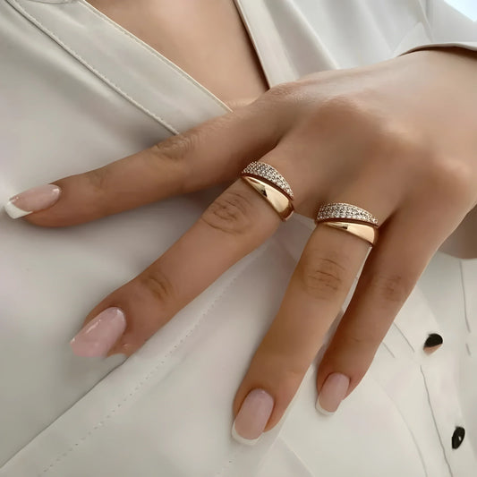 Par de anillos de oro con piedras brillantes tipo banda, en la mano