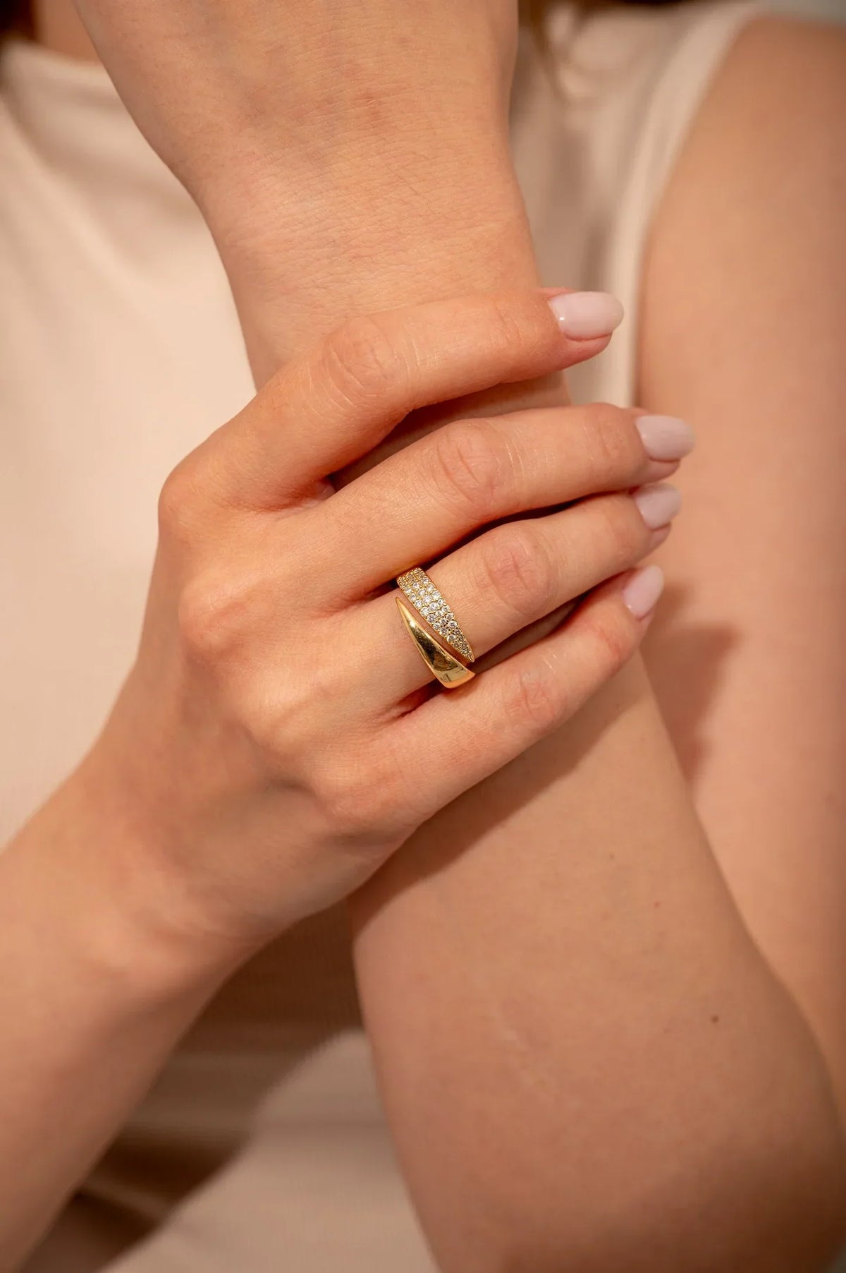 Anillo dorado con banda brillante y filas de piedras en el dedo