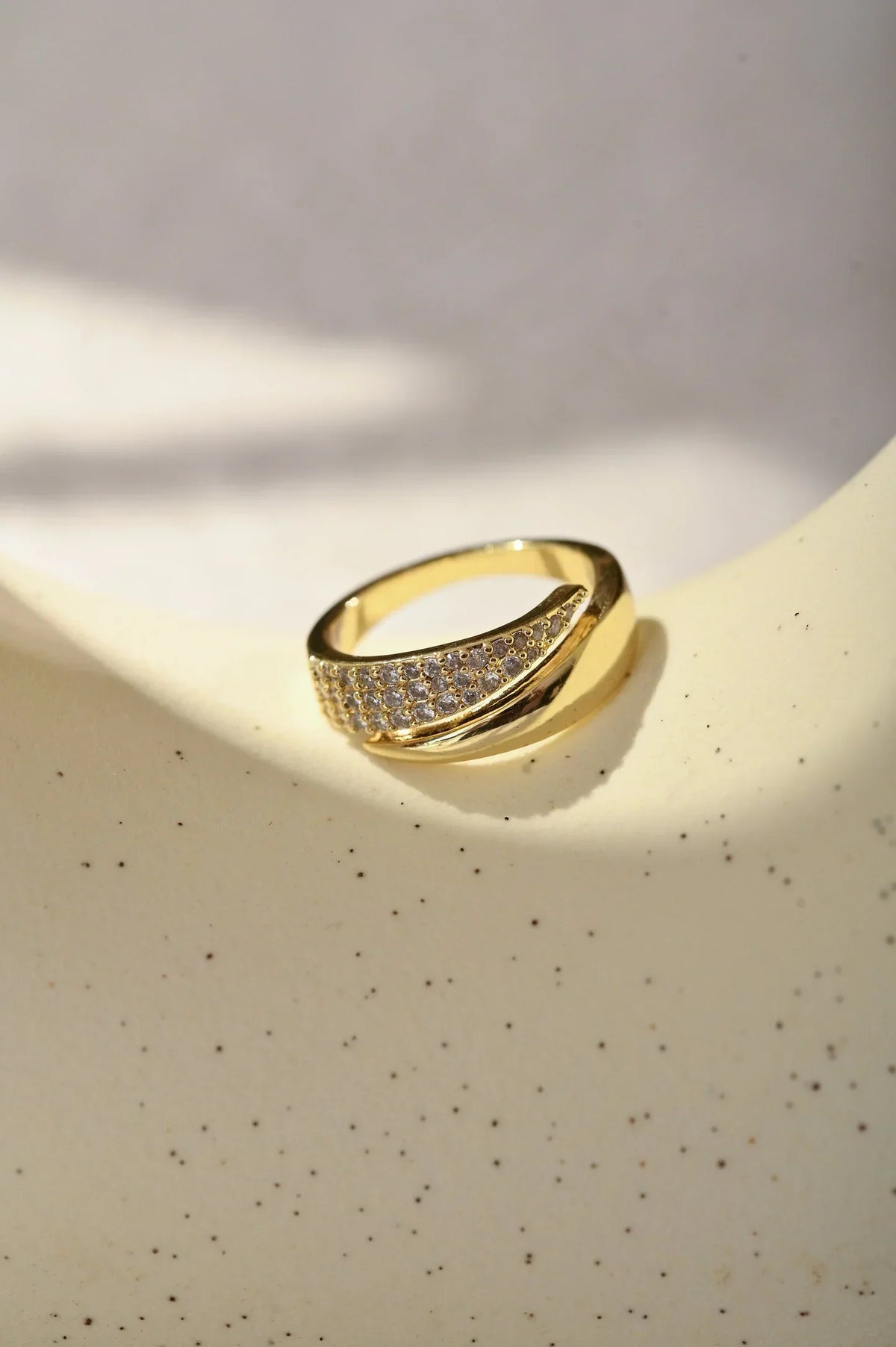 Anillo dorado con sección de piedras brillantes, acabado curvo