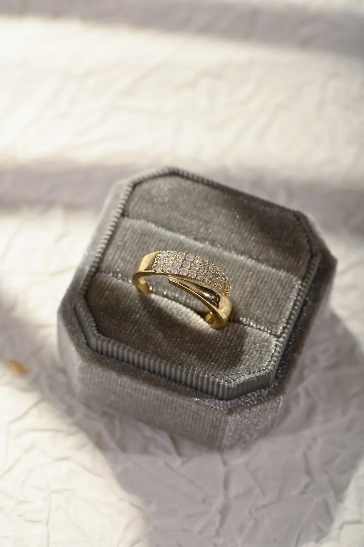 Anillo dorado con banda de piedras brillantes en estuche de terciopelo