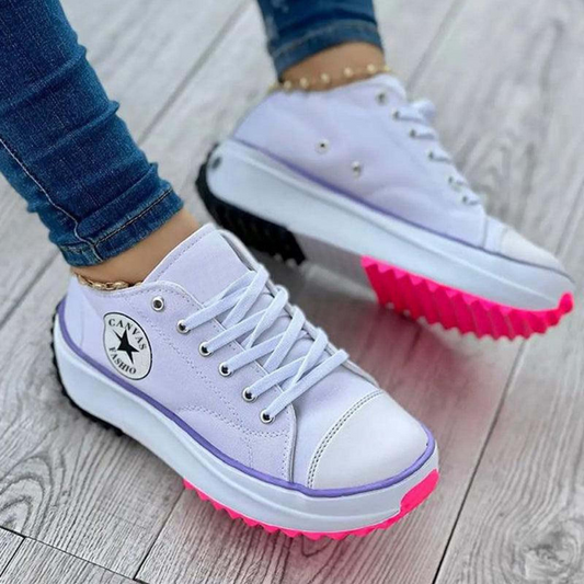 Zapatillas ortopédicas blancas con borde lila, cordones y suela fucsia marcada.