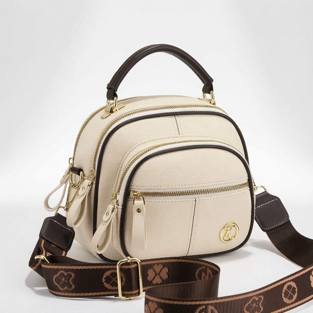 Bolso bandolera compacto de cuero beige con doble compartimento y cremallera frontal, placa K.