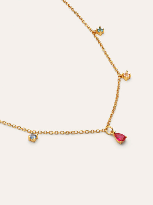 Collar dorado con dijes móviles: gota roja y corazones azules, vista cercana