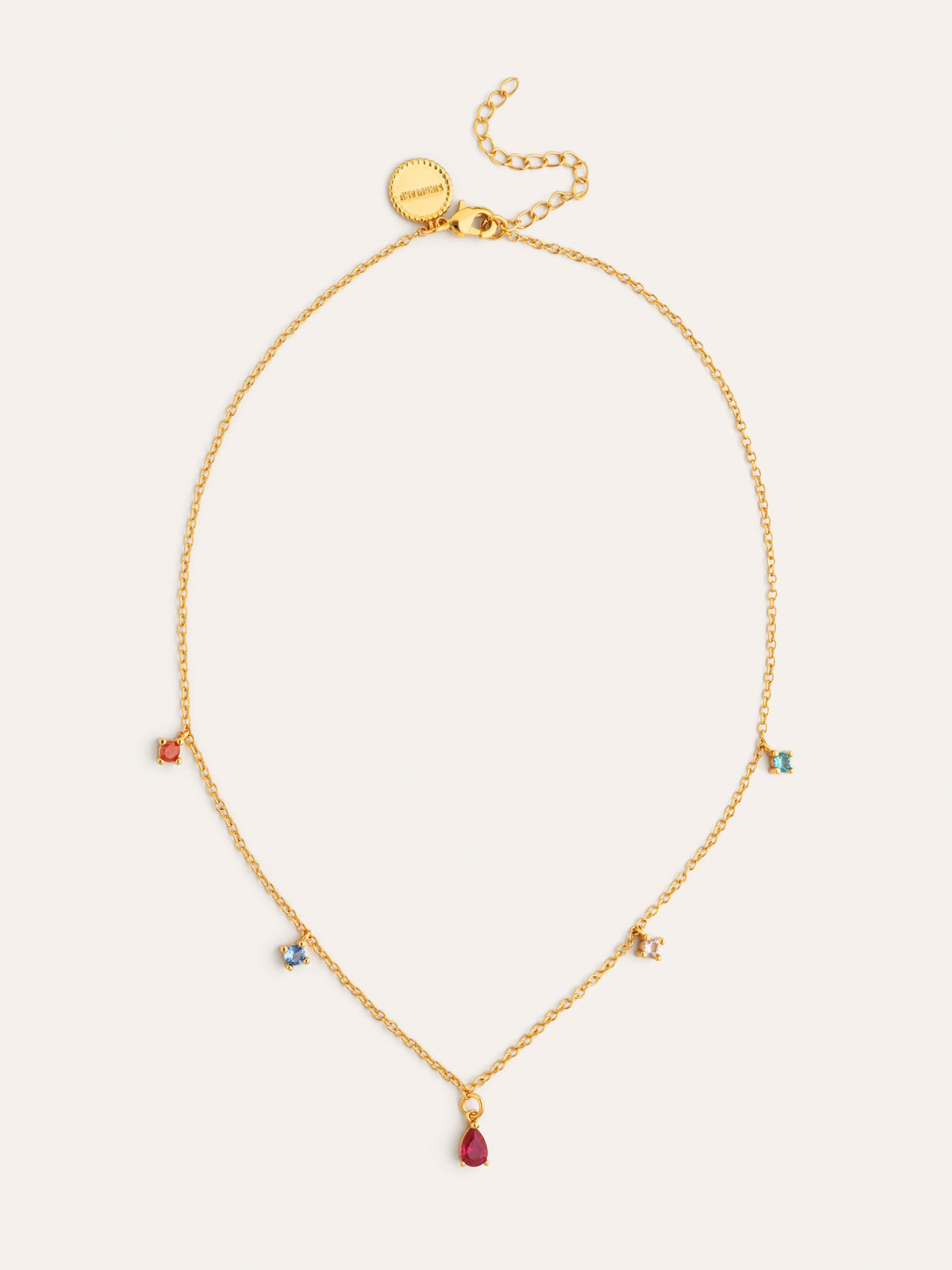 Collar dorado con dijes: gota roja y pequeños charms azules y plateados