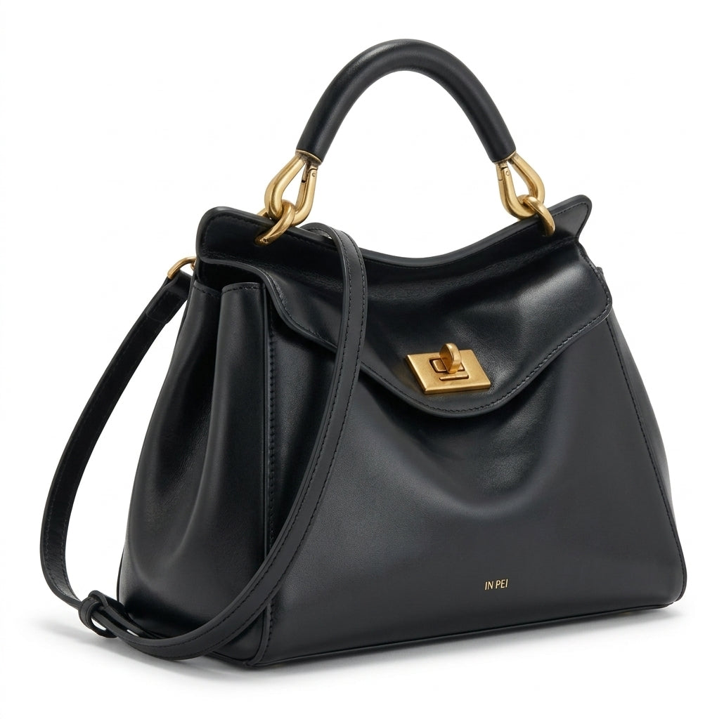 Bolso de piel lisa negro con solapa frontal y bandolera ajustable, cierre metálico.