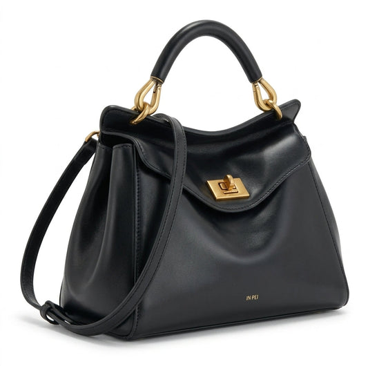 Bolso de piel lisa negro con solapa frontal y bandolera ajustable, cierre metálico.