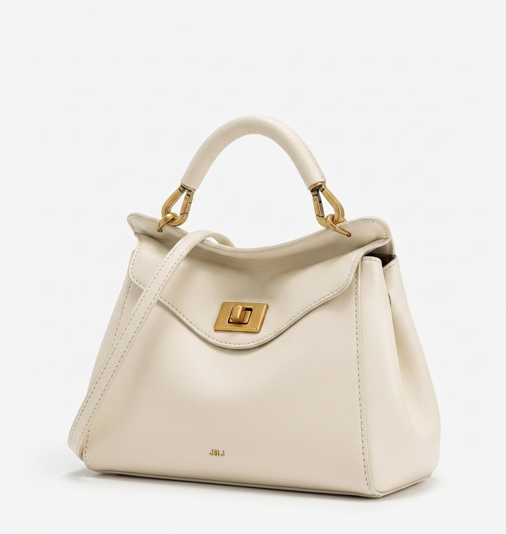 Bolso de piel lisa beige con asa de arco y bandolera, solapa frontal con cierre metálico.