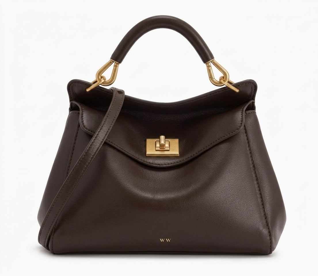 Bolso de piel lisa marrón oscuro con asa corta y bandolera, solapa con cierre metálico.